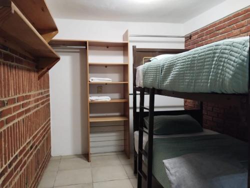 a room with a bunk bed and a brick wall at Xaltepic tú casa in Amecameca de Juárez