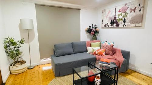 a living room with a blue couch and a glass table at House in Sunshine close to city in Sunshine