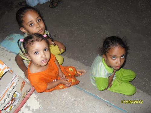 three young girls sitting on the floor next to a book at Villa Diletta Luxor in Luxor
