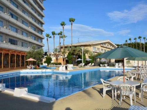 a large swimming pool with chairs and an umbrella at Shodoshima International Hotel in Tonosho