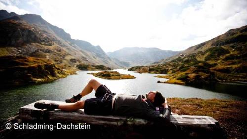 a man laying on a rock next to a river at Haus Panorama in Schladming