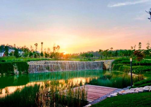 einen Teich mit einer hölzernen Promenade vor einem Sonnenuntergang in der Unterkunft New Rawang Hotel in Kuala Lumpur