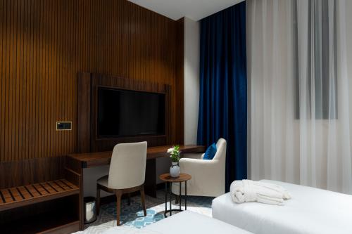 にあるFergana Hotel Tashkentのベッドと机とテレビがあるホテルの部屋