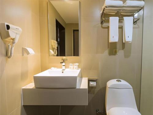 a bathroom with a sink and a toilet and a mirror at Jtour Inn Suizhou Yanhe Avenue in Suizhou