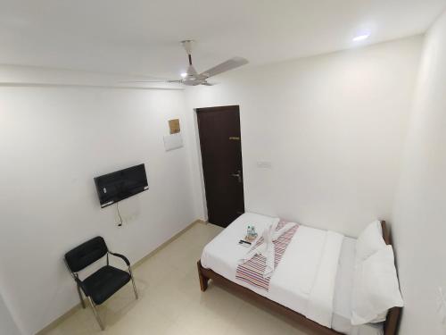 a white room with a bed and a chair at Goldwins Grand A comfort stay in Coimbatore