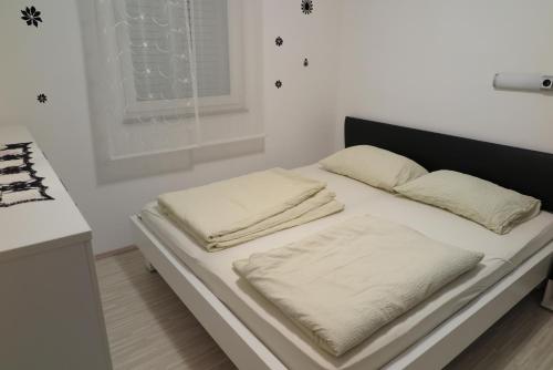 a bed with white sheets and pillows on it at Apartment Omerovic in Novalja