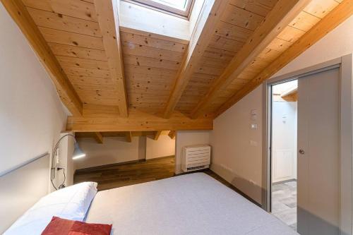 a bedroom with a wooden ceiling with a window at Residenza Cavour - Appartamento D in Tirano