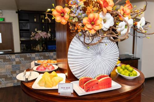 a table with fruit and a large vase with flowers at A25 Hotel - 29 Lê Thị Hồng Gấm in Ho Chi Minh City