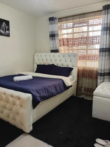 a bedroom with a large white bed and a window at Jeff HOMES Bnb in Nakuru