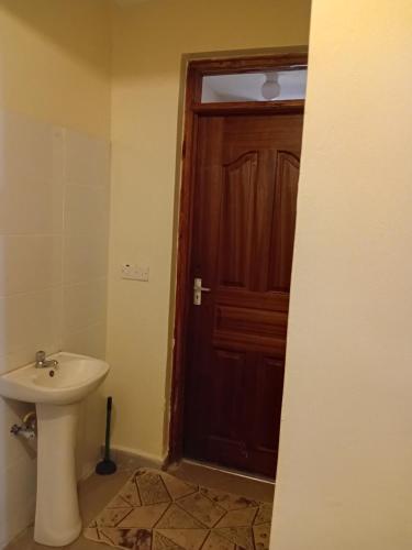 a bathroom with a sink and a wooden door at Jeff HOMES Bnb in Nakuru