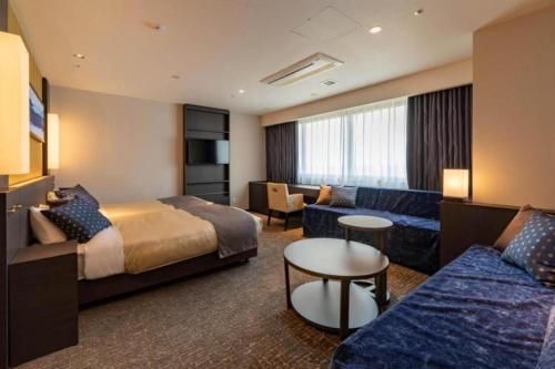 a hotel room with a bed and a couch at HOTEL BAYGULLS in Izumi-Sano