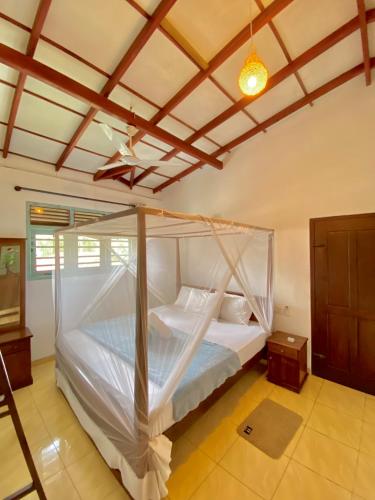 a bedroom with a bed with a mosquito net at Coco Bliss - Ahangama in Ahangama