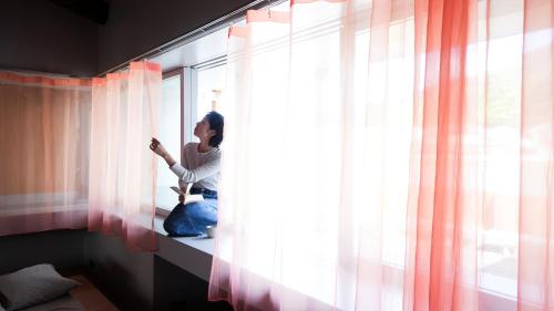 Eine Frau, die auf einer Fensterscheibe sitzt und rausschaut. in der Unterkunft SEW STAY Slow Seam KYOTO MAIZURU in Maizuru