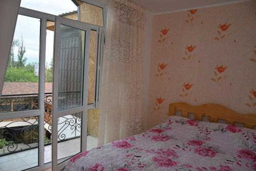 a bedroom with a bed and a balcony at Guest House Albatros in Cholpon-Ata