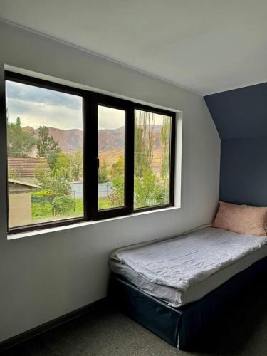 a bedroom with three windows and a bed in it at Nomad House in Yur'yevka
