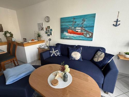 a living room with a blue couch and a table at Knechtsand 402 in Cuxhaven