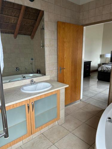 a bathroom with a sink and a bath tub at Daisy Accommodation & Spa in Cape Town