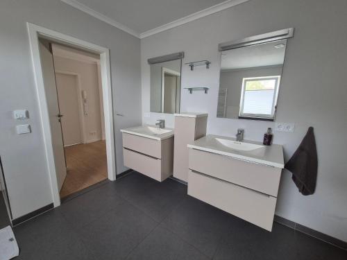 un bagno bianco con due lavandini e uno specchio di Sunny Flensbo Apartment a Flensburgo