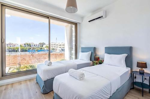 Dos camas en una habitación con una gran ventana. en Azure Luxe Villas, en Protaras