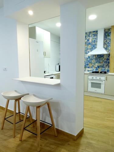 a white kitchen with two stools and a counter at Hoya del Agua Casa Rural in Casas de Haro
