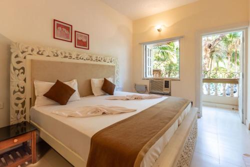 a bedroom with a large bed in a room with two windows at AV apartment beach candolim in Aguada