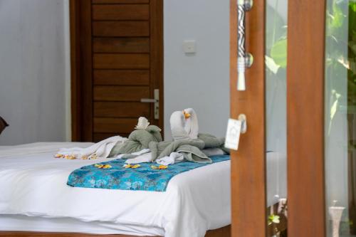 a bed with two stuffed animals on top of it at Holiday Guest House in Amed