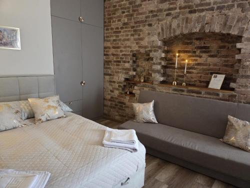 a bedroom with a bed and a couch in front of a brick wall at Placeo in Katowice