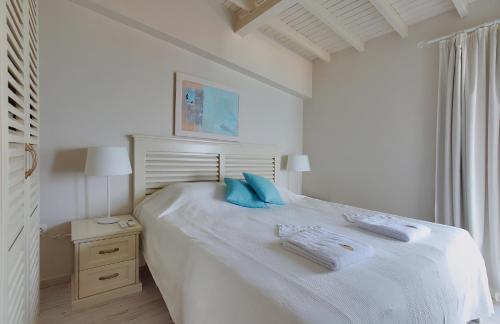 a white bedroom with a large white bed with blue pillows at Kabakum Holiday Houses in Golden Sands