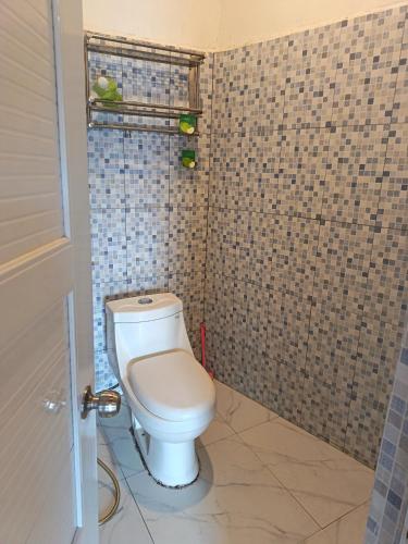 a bathroom with a toilet and a tiled wall at Satera Homestay in Seteluk