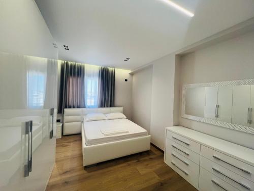 a white bedroom with a bed and a mirror at Sea view apartament in Durrës