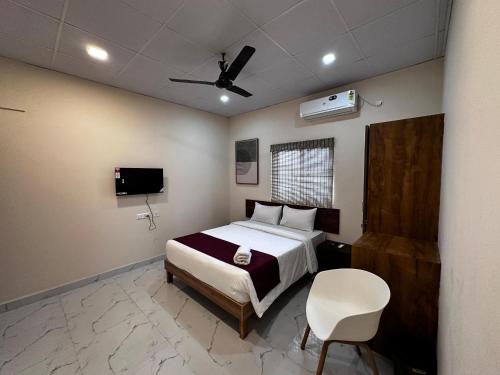 a bedroom with a bed and a chair and a tv at Urbanstay Service Appartment in Bengaluru