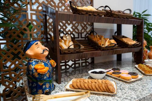 een tafel bedekt met brood en gebak en een beeldje bij Fergana Hotel Tashkent 