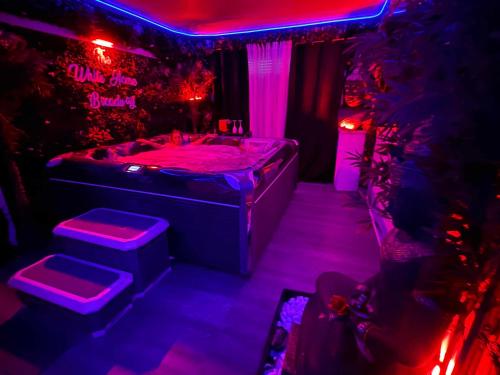 a dark room with a bed with purple lights at The White Home Broadway Love Room in Châteauroux