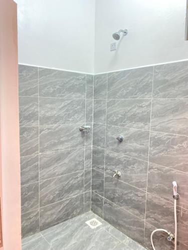 a shower with a gray tiled wall at Bright rooftop pool studio in Mtwapa, Fast Wi-Fi ,Free parking ,Near Beach in Mtwapa