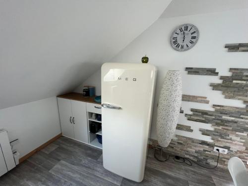 a white refrigerator in a room with a clock on the wall at Le petit Kichon in Gérardmer
