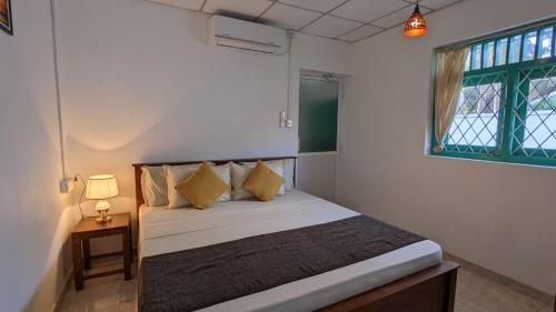 a bedroom with a bed with a lamp and a window at Villa Coleus in Tangalle
