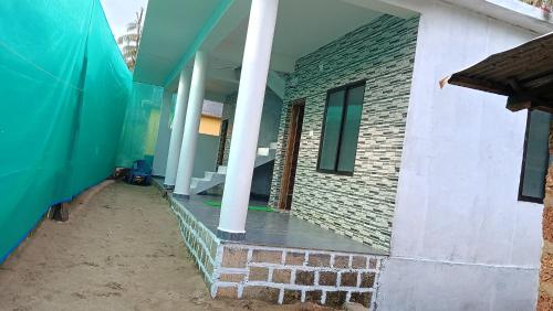 a house with a brick wall and white columns at Sateri Homestay Gokarna Beach in Gokarn
