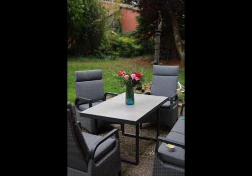 a table with chairs and a vase of flowers on it at Studio Ohlendorf 3 Min zur A7 in Seevetal