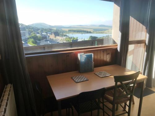 ein Tisch und Stühle in einem Raum mit einem großen Fenster in der Unterkunft Appt 4 prs Tour de La Biche depart skis aux pieds in Besse-et-Saint-Anastaise