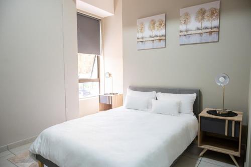 a bedroom with a large white bed and a window at Rosebank Luxury Loft in Johannesburg