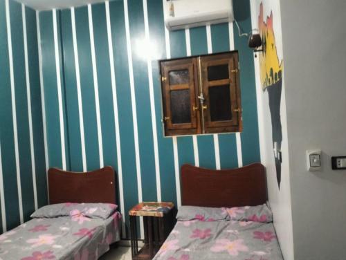 two beds in a room with green and white stripes at Safy Guest House in Jazīrat Aswān