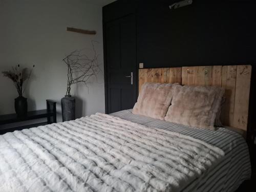 a bedroom with a large bed with a wooden headboard at Gîte de La Blanche Ferme près de Pairi Daiza in Lessines