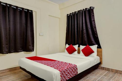 a bedroom with a bed with red pillows at Hotel O Sai Avenue in Pune