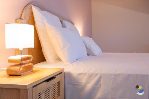 een bed met witte lakens en een lamp op een nachtkastje bij Dodoterla - BoisBlanc in Sainte-Rose