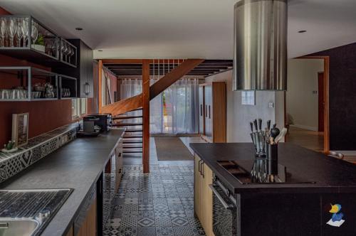 een keuken met zwarte aanrechtbladen en een trap bij Dodoterla - BoisBlanc in Sainte-Rose