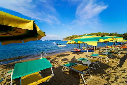 een strand met stoelen en parasols en de oceaan bij Residence in Capoliveri just 200 mt from the beach in Capoliveri