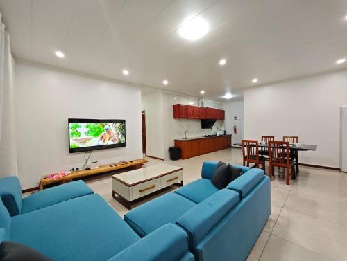 a living room with blue couches and a flat screen tv at Alice 3-bedroom luxury apartment in Nadi