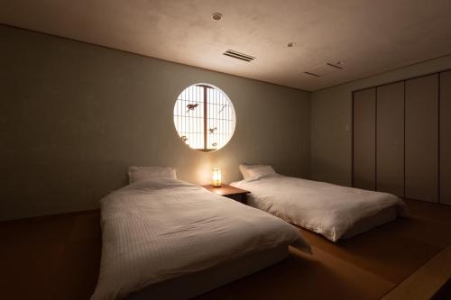 a bedroom with two beds and a round window at 蘇生の宿Samsara Inn - 1日1組の特別な宿 - in Tanabe