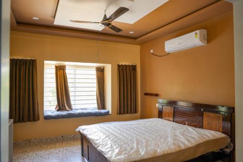 a bedroom with a bed and a ceiling fan and a window at SPK farmhouse in Medchal