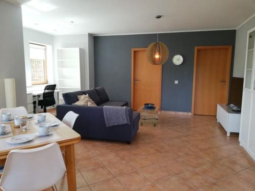 a living room with a blue couch and a table at Himmelthal Apartment in Eschau